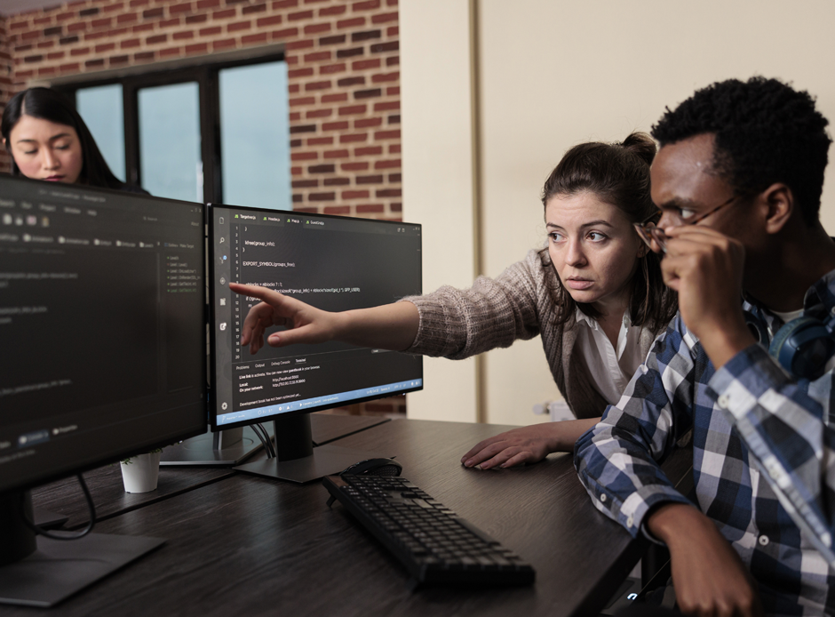 Mulher Apontando para Tela do Computador e Homem Analisando Dados Mulher Apontando para Tela do Computador e Homem Analisando Dados
